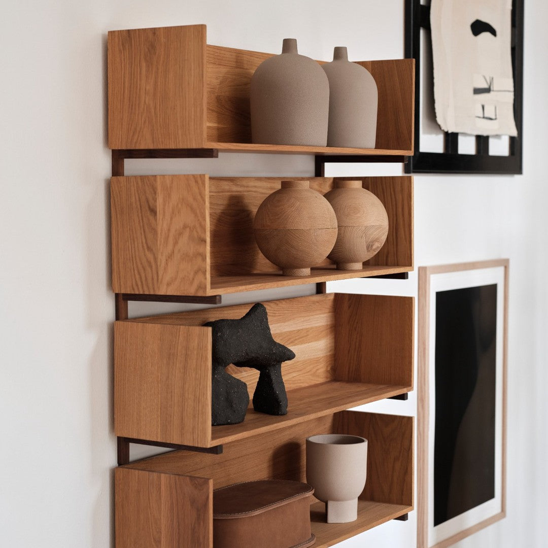 Wooden shelf with warm oak tones, showcasing various neutral ceramic vases and textured decor in a minimalistic layout.