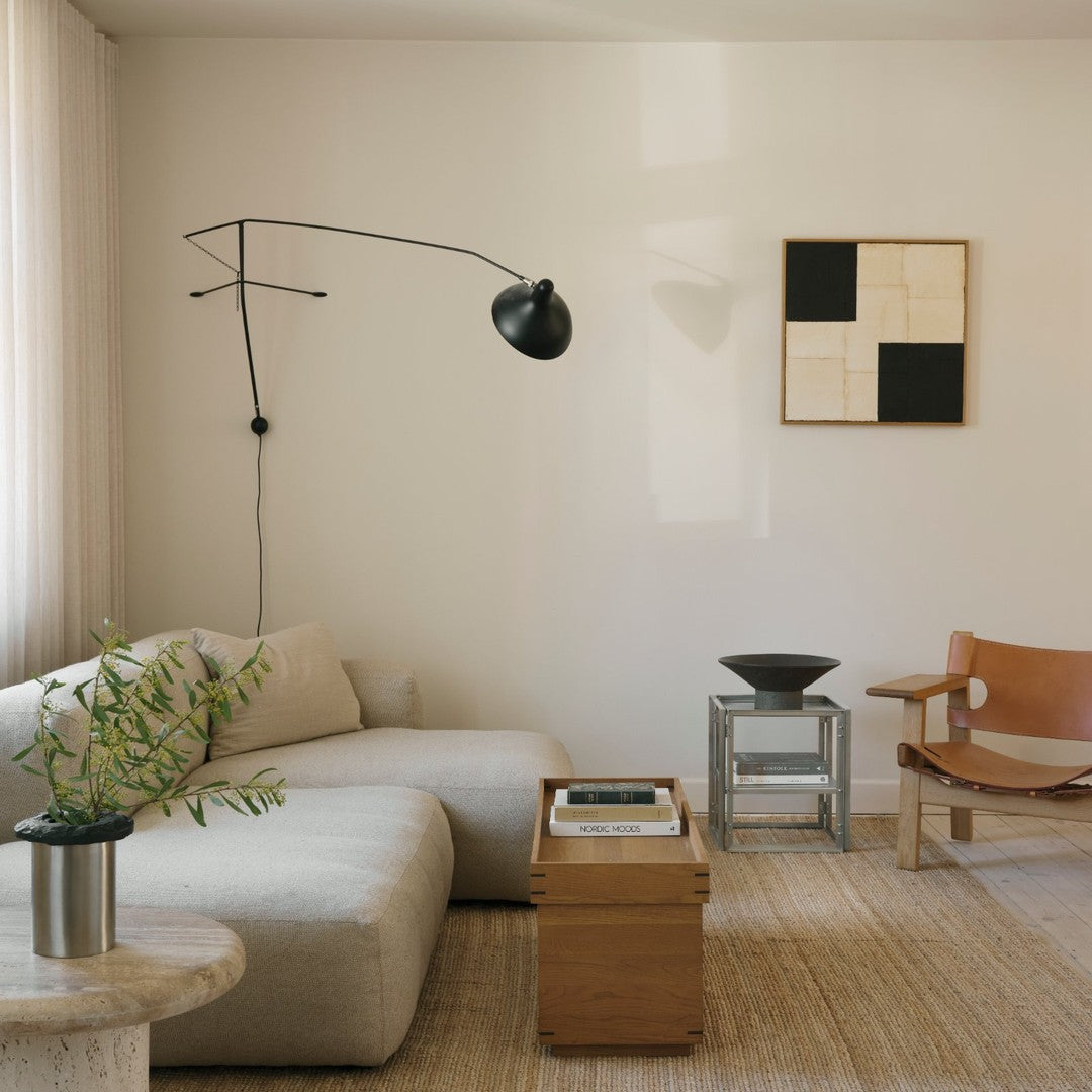 Modern living room featuring neutral beige sofa, black lamp, minimalist art with black and white colors, and natural textures.