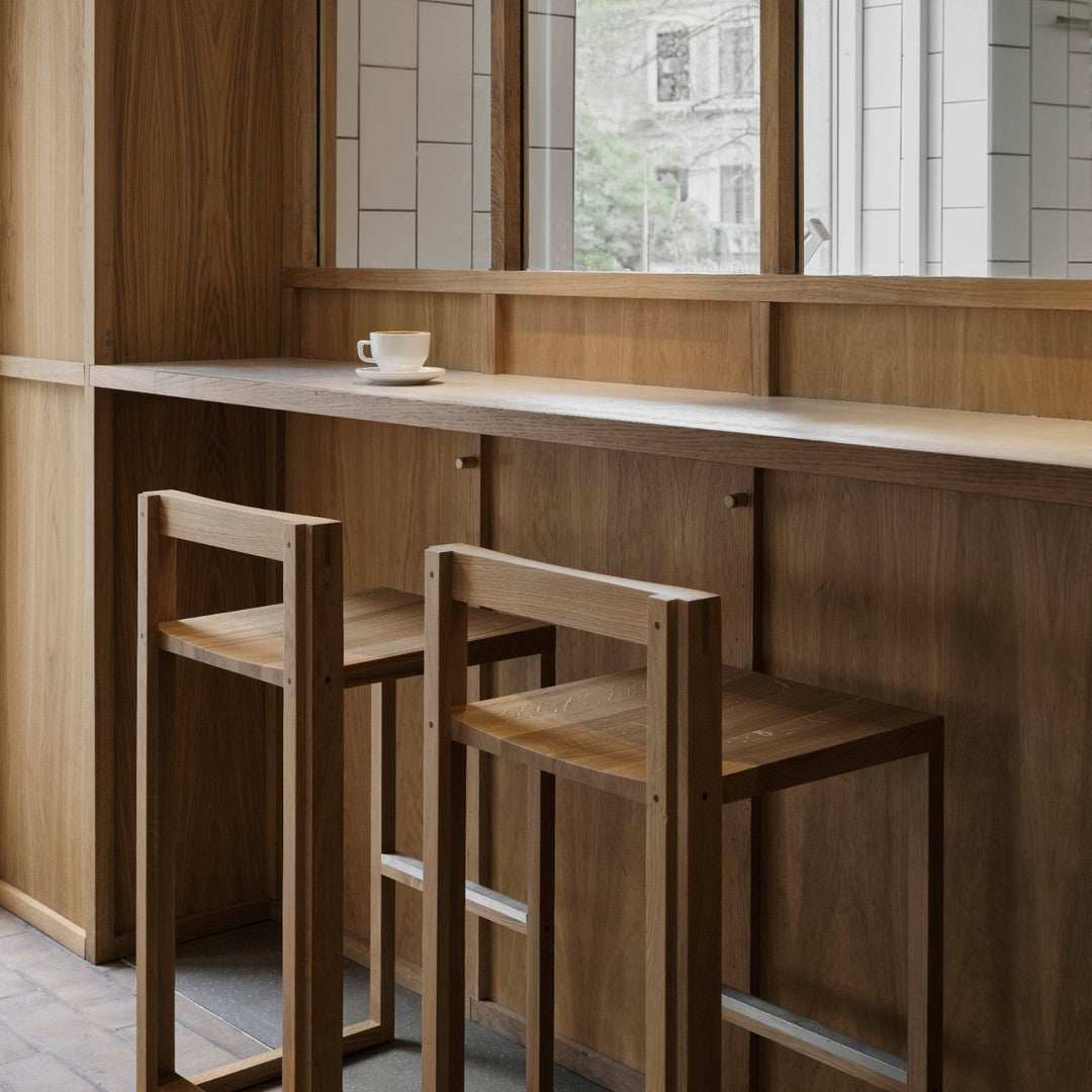 Wooden bar stools with minimalist design, natural wood finish, and neutral tones in a modern, airy space.