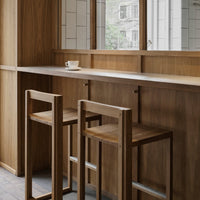 Wooden bar stools with minimalist design, natural wood finish, and neutral tones in a modern, airy space.