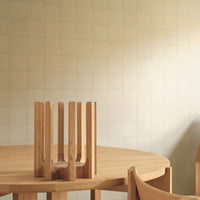 Natural wood table centerpiece with vertical slats, set against a light beige grid-patterned wall.