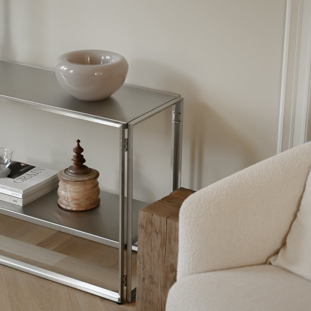 Stylish silver metal console table with a smooth gray surface, paired with neutral tones of beige and cream.