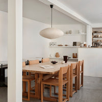 Light wood dining table with natural grain, paired with minimalist beige chairs. Soft, neutral tones create a serene atmosphere.