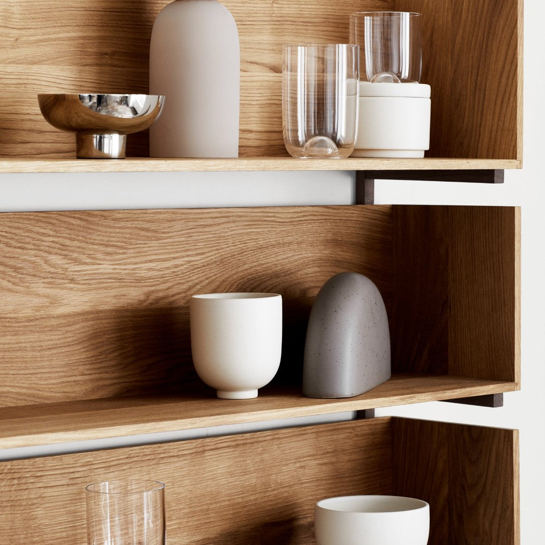 Neutral color vases and glassware showcased on wooden shelves, featuring soft textures and minimalist designs.