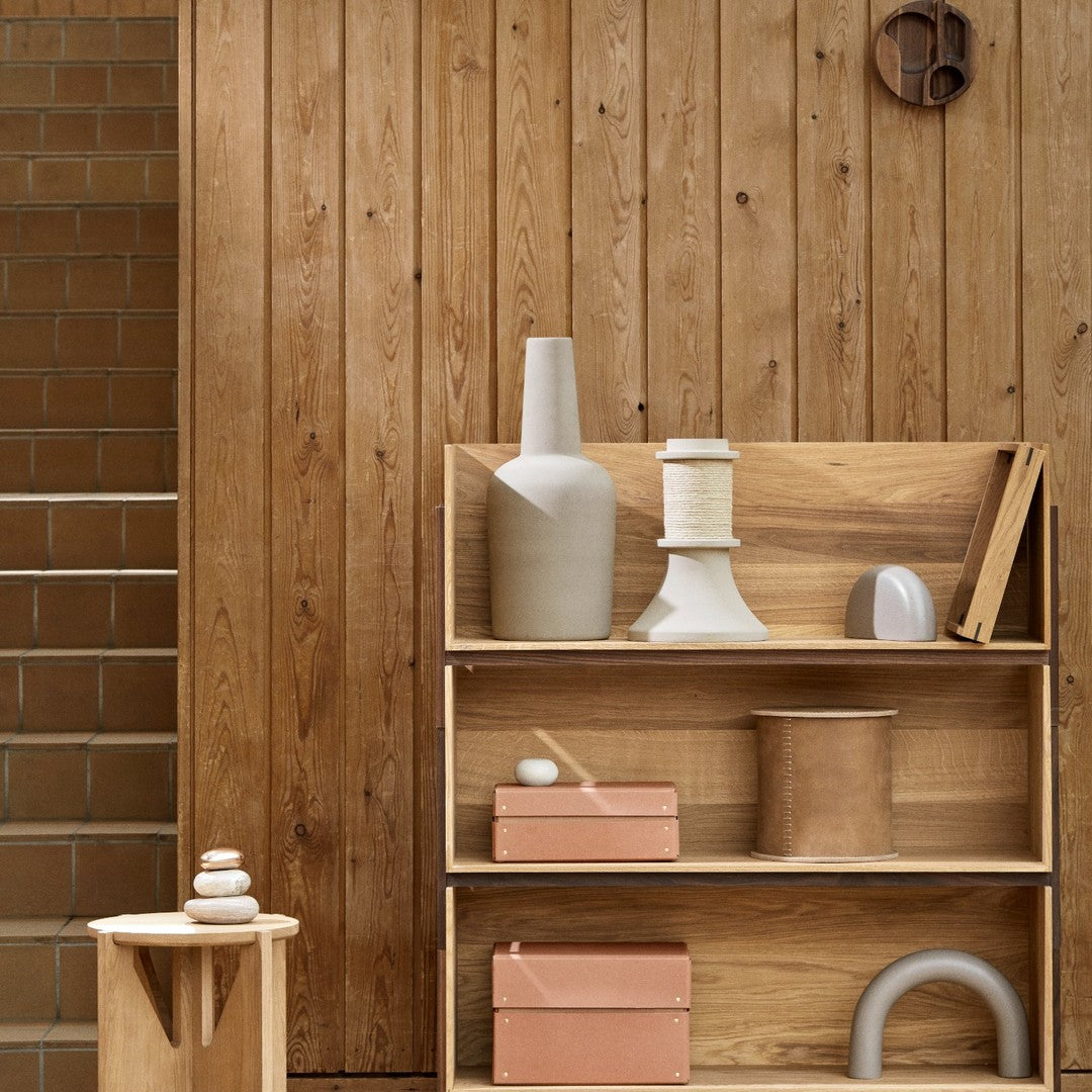 Wooden shelves showcasing neutral tones, soft pastels, and various geometric patterns against a warm wood backdrop.