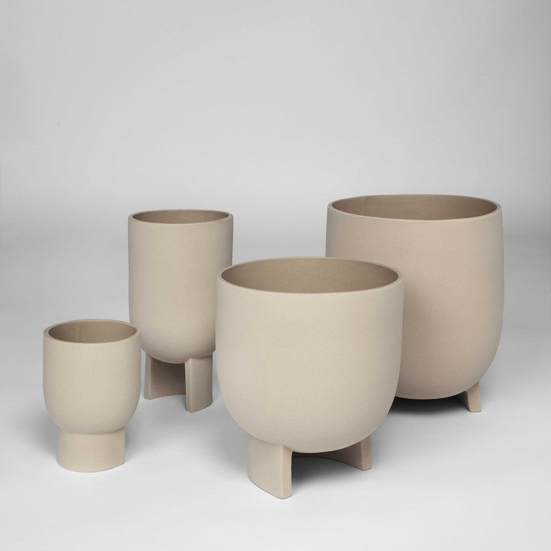 Set of four minimalist beige ceramic plant pots with smooth, matte finishes and varied heights. Perfect for modern decor.