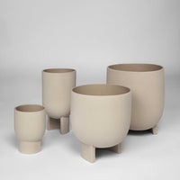 Set of four minimalist beige ceramic plant pots with smooth, matte finishes and varied heights. Perfect for modern decor.