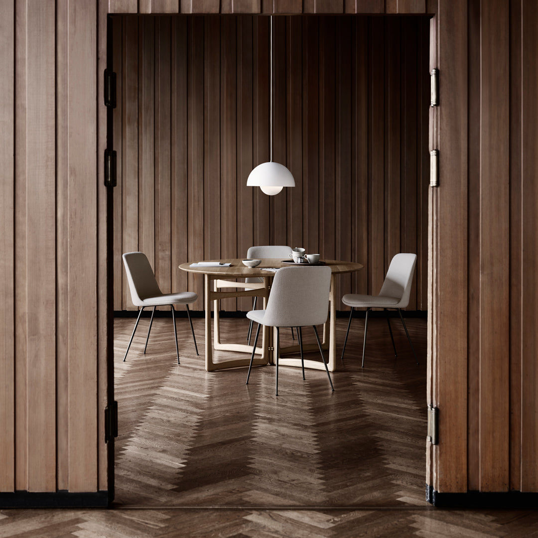 Modern dining room featuring wood-paneled walls, herringbone floor, and neutral-tone furniture. Elegant and minimal design.