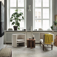 Cozy living room with neutral tones, green plants, a pop of yellow, and subtle patterns in the furniture and decor.