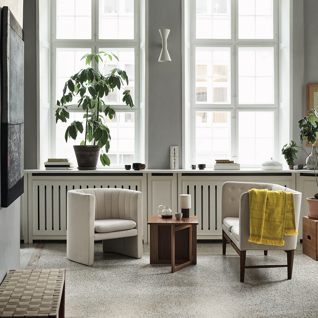 Cozy living room with neutral tones, green plants, a pop of yellow, and subtle patterns in the furniture and decor.