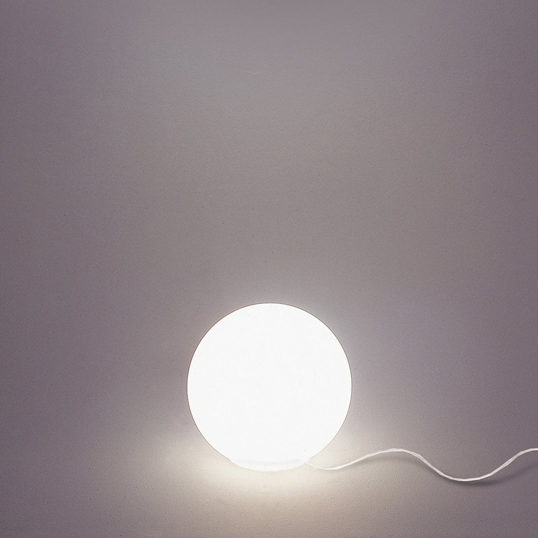 Round white lamp with a smooth surface, set against a soft gray background. Minimalist design with a subtle glow.