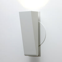 Sleek white wall sconce with a geometric design and smooth surfaces, highlighting modern minimalist decor.