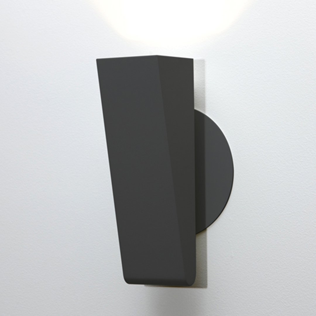 Modern black wall sconce with a geometric design and matte finish, featuring a circular base.