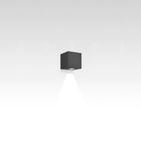 Sleek black cube wall lamp casting a focused beam of light against a minimalist white background.