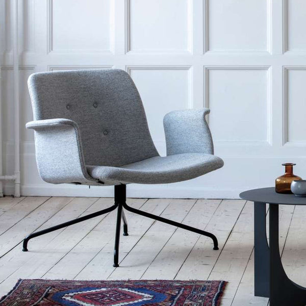 Gray upholstered chair with sleek lines and subtle button detailing, set on a black metal base. Cozy modern aesthetic.