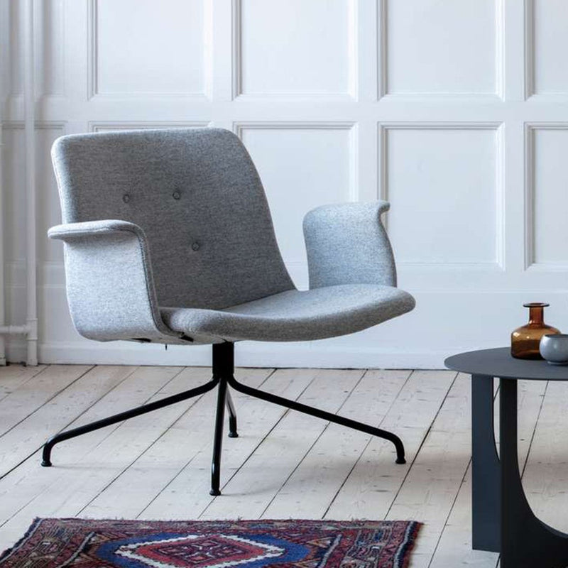 Gray upholstered chair with sleek lines and subtle button detailing, set on a black metal base. Cozy modern aesthetic.