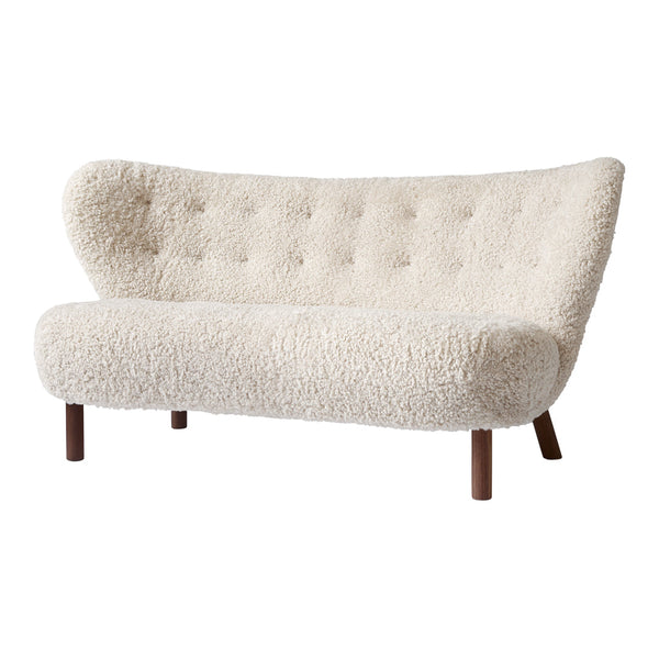 Cream-colored tufted sofa with a curved shape and plush faux sheepskin texture. Warm wooden legs enhance its modern aesthetic.