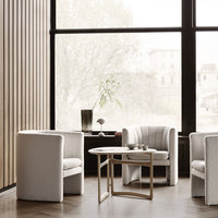 Elegant white upholstered chairs with soft texture, paired with a minimalist wooden coffee table in a bright, airy setting.