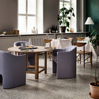 Elegant gray chairs with soft curves around a wooden table, complemented by natural tones and greenery in a modern setting.