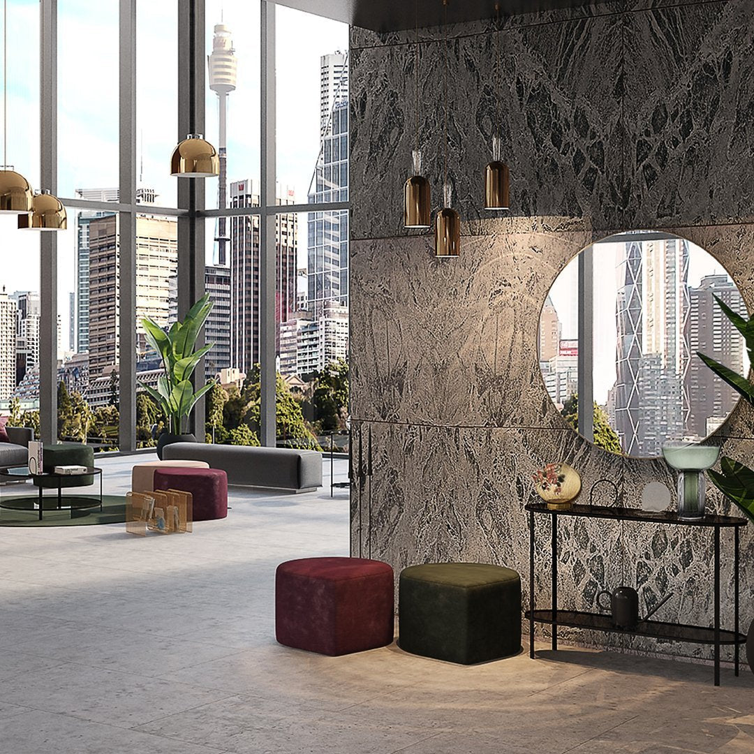 Contemporary interior with textured gray walls, green and burgundy poufs, and stylish gold light fixtures.