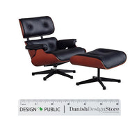 Black leather chair with brown wood accents, featuring a sleek, modern design and matching ottoman.