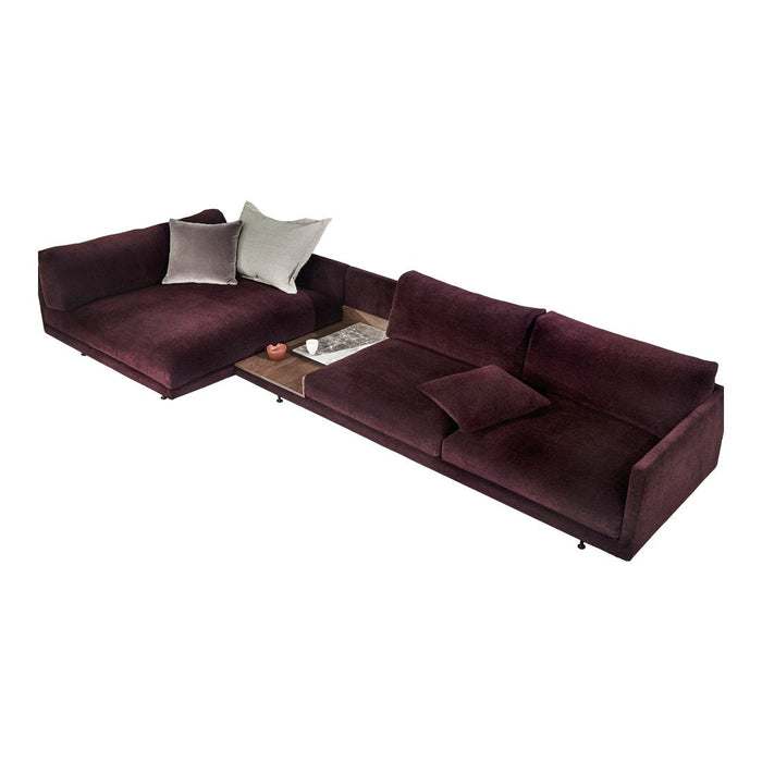 Plush burgundy sectional sofa with soft velvet texture and scattered neutral throw pillows. Modern, elegant design.