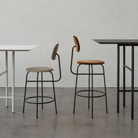 Stylish bar stools in muted grey and brown with sleek black metal bases, complemented by minimalist white and black tables.