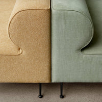 Sofa featuring a textured golden yellow side and a soft green side, both with rounded edges and black legs.