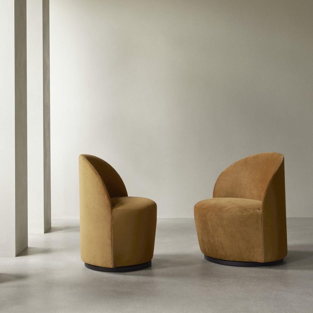 "Two modern chairs in warm tan suede with sleek curves and minimalistic design against a neutral backdrop."