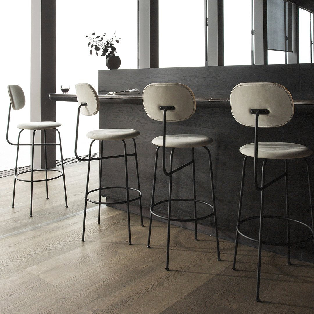 Modern bar stools with soft beige seats and sleek black metal frames, featuring minimalist design and neutral tones.