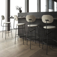 Modern bar stools with soft beige seats and sleek black metal frames, featuring minimalist design and neutral tones.
