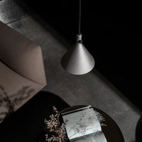 "Modern silver pendant lamp with a sleek conical design, illuminating a cozy, dark-toned living space."