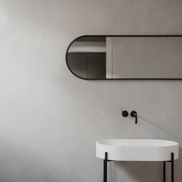 Modern bathroom featuring a white basin, black fixtures, and a sleek black mirror against a soft gray wall.