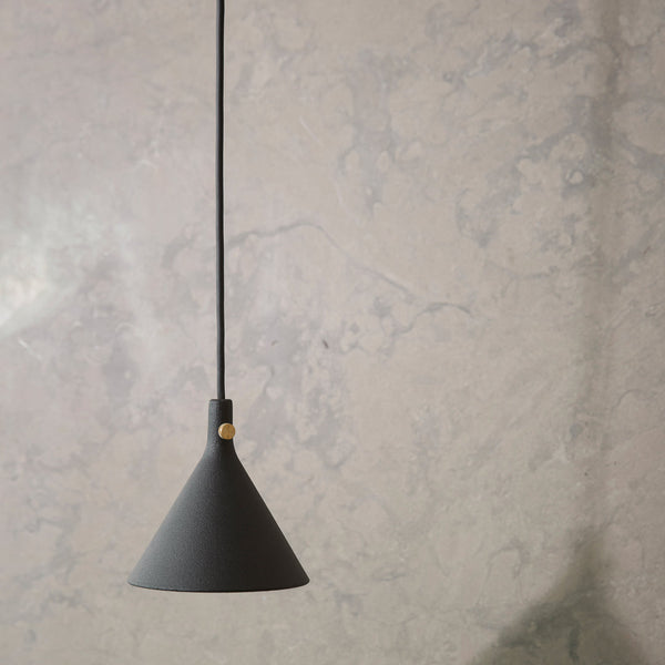 Black conical pendant lamp with a sleek matte finish, suspended against a textured gray wall.
