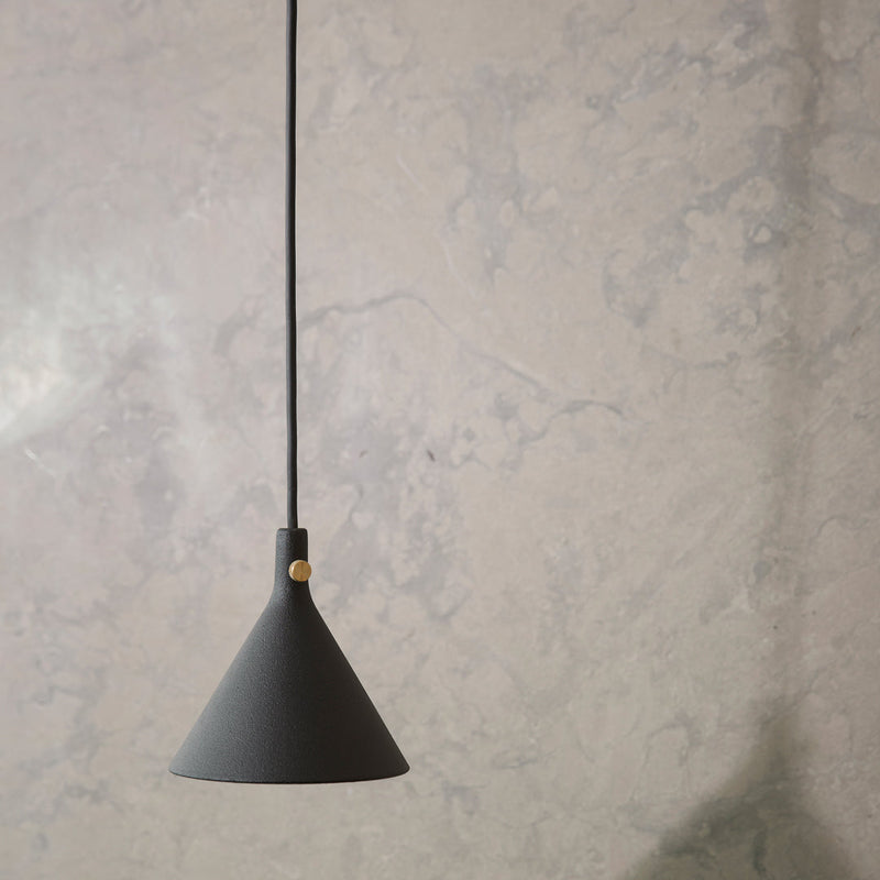 Black conical pendant lamp with a sleek matte finish, suspended against a textured gray wall.