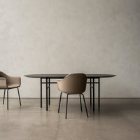 Elegant black oval dining table with beige upholstered chairs on a light textured background. Modern minimalist design.