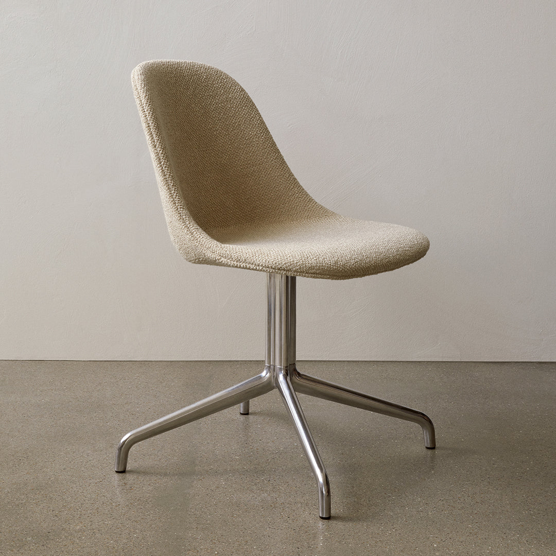 Beige upholstered chair with a smooth, curved silhouette and a sleek silver base, set against a neutral background.