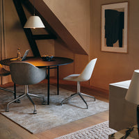 Modern workspace featuring a round black table, soft gray chairs, and a neutral-toned rug, enhancing minimalist aesthetics.