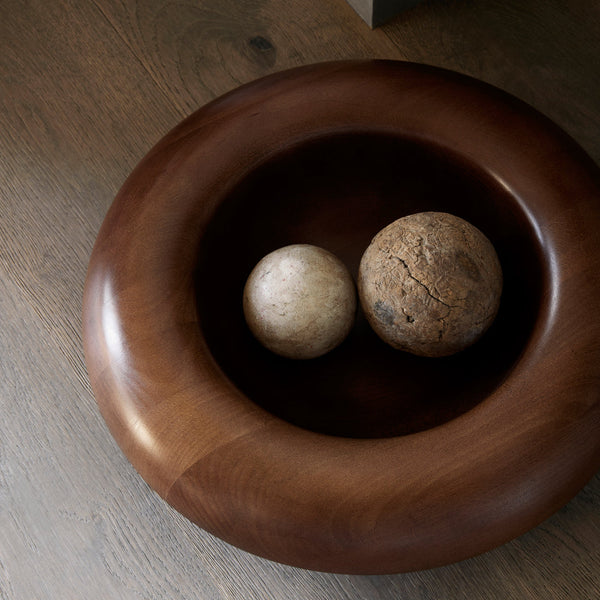 Brown wooden bowl with smooth finish, featuring light beige and textured brown decorative spheres inside.