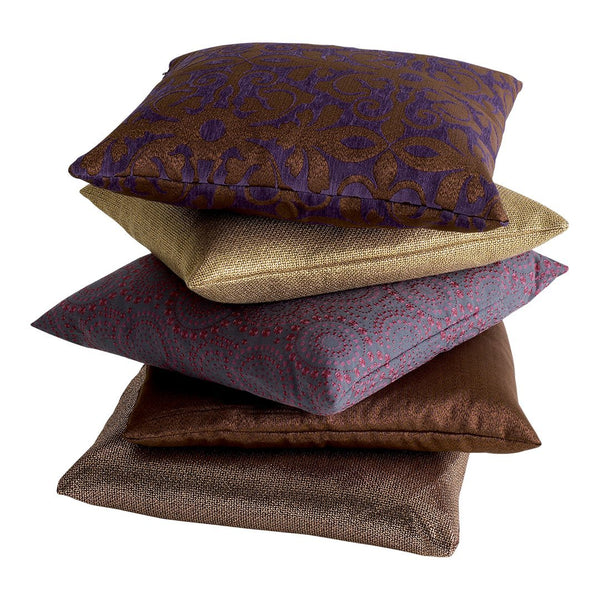 Vibrant decorative pillows in rich purple, gold, brown, and lavender with intricate patterns and textures.