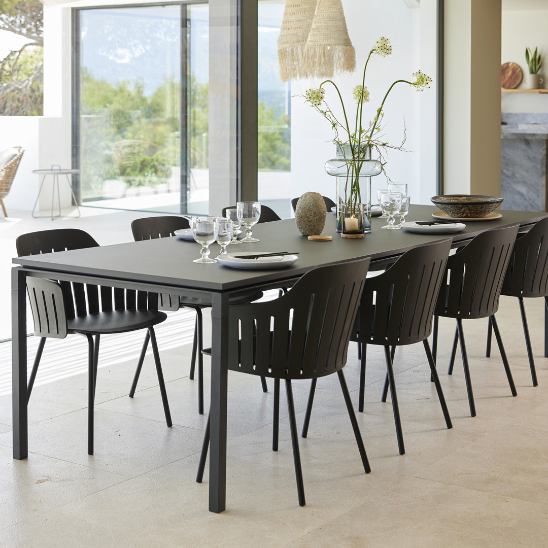 Modern black dining table with sleek lines, paired with black ribbed chairs in a minimalist setting.