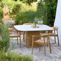 Modern outdoor dining set with a white tabletop and natural wooden chairs, featuring subtle earthy hues and smooth lines.
