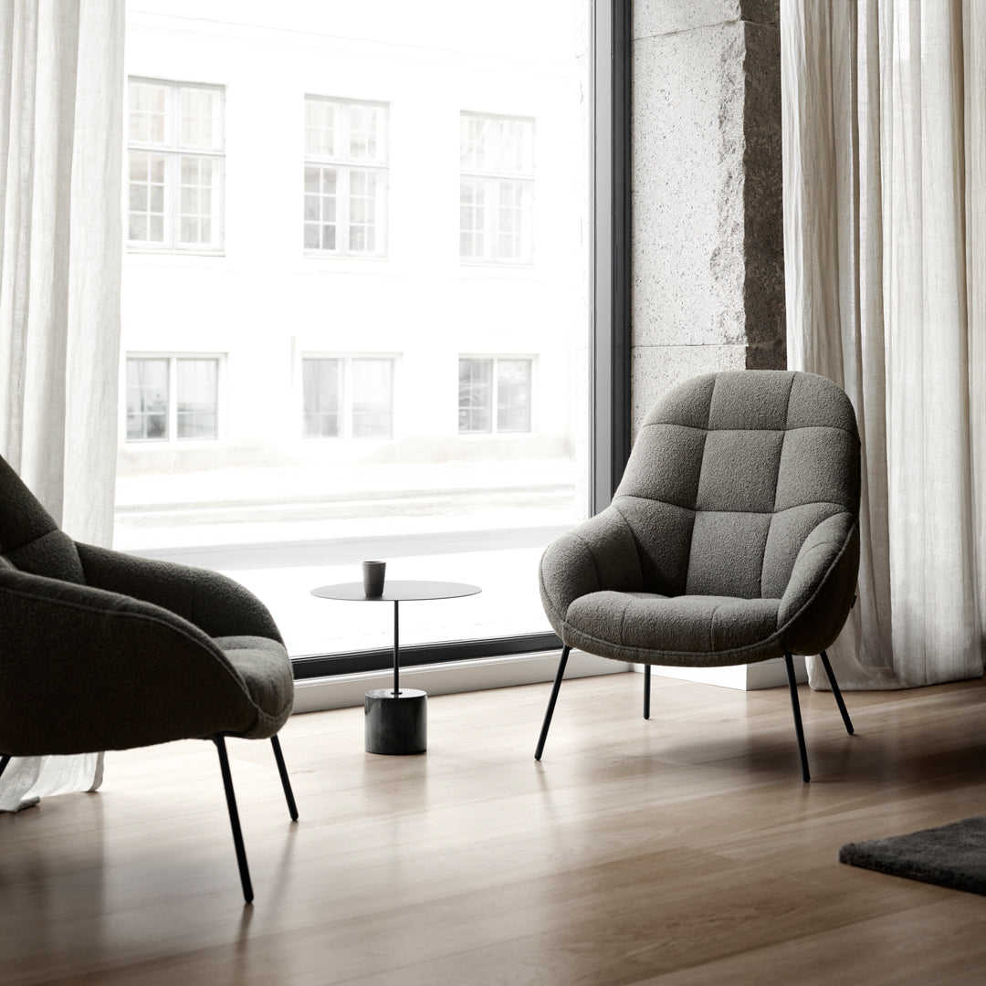 Sleek gray armchair with a soft, quilted pattern against a light-filled modern interior.