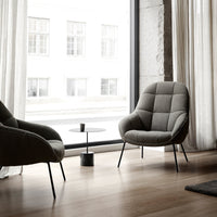 Sleek gray armchair with a soft, quilted pattern against a light-filled modern interior.