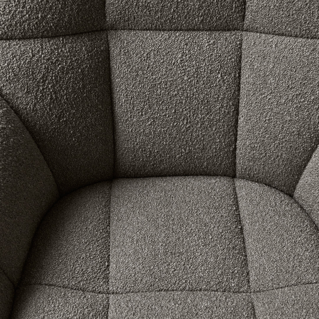 Gray textured fabric with a subtle tufted pattern on a cushioned chair. Ideal for modern decor.