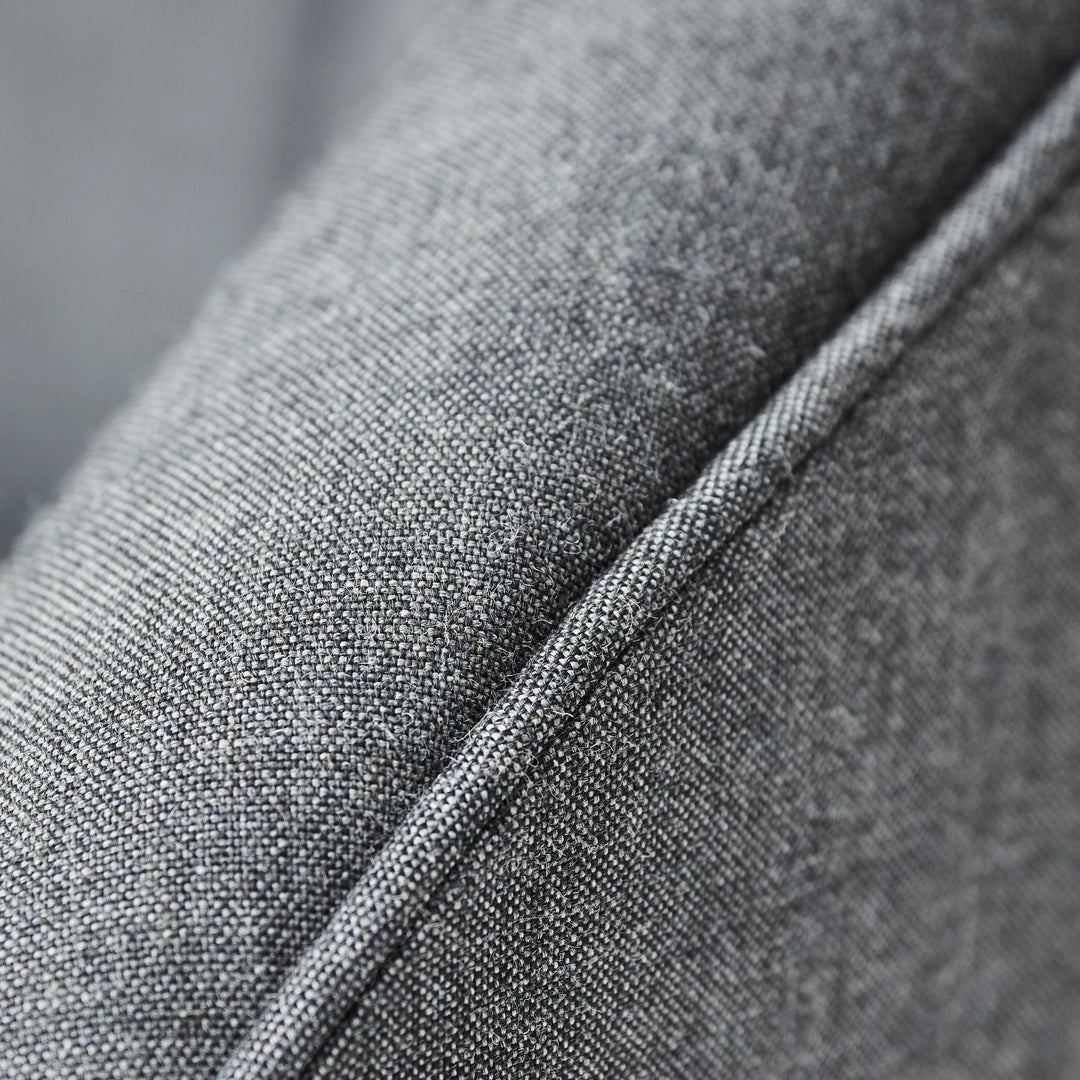 Close-up of textured gray fabric with subtle diagonal weave pattern and contrasting stitch detail.
