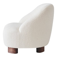 Textured white upholstery on a curved chair with wooden legs, offering a minimalist and cozy aesthetic.