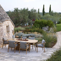 "Outdoor dining set featuring natural wood tones and soft gray cushions against a lush green garden backdrop."