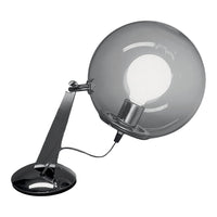 Sleek chrome desk lamp with a clear round glass shade and black base, creating a modern, minimalist aesthetic.