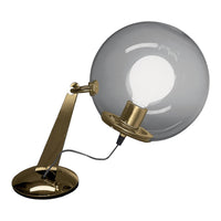 Stylish brass lamp with a round, clear glass shade, featuring a sleek modern design.
